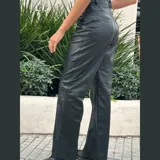 Pantalón de cuero negro de tiro medio y pierna recta con tajo en el ruedo.