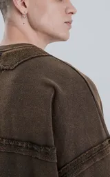 Buzo marrón de cuello redondo con costuras expuestas, calce oversize crop y proceso de desgaste.