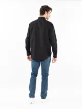 Camisa negra de manga larga con cuello clásico, cierre frontal con botones, bolsillo de parche en el pecho y logo Calvin Klein.
