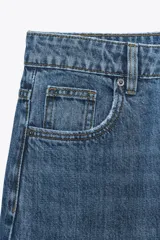 Pantalón de jean azul oscuro, de corte wide leg y tiro medio, con cinco bolsillos y cierre frontal con cremallera y botón metálico.