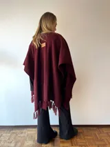 Ruana bordó de tejido acrílico con flecos.