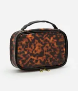 Neceser rectangular grande de plástico transparente con estampado de carey en tonos marrones. Tiene cierre de cremallera doble dorada, asa de mano negra y ribete negro.