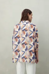 Camisa estampada con figuras geométricas en tonos azul, marrón y beige. Corte relajado, manga tres cuartos y botones al frente.