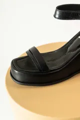 Sandalias de cuero color marrón con plataforma y taco de cuña. Tiras anchas con textura tipo cocodrilo y hebilla metálica plateada.