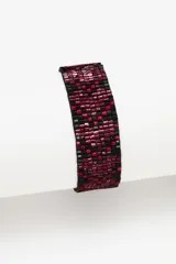 Pulsera tejida con pequeñas cuentas de vidrio rojas y negras, con cierre ajustable mediante cordones negros.