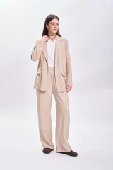 Pantalón de vestir beige de corte palazzo, con cintura alta y bolsillos laterales.