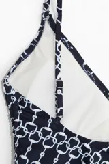 Traje de baño enterizo negro con estampado de cadenas blancas, escote en V, tirantes finos y cordones laterales para ajustar el fruncido.