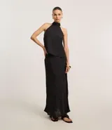 Pollera midi de corte recto confeccionada en crepé negro con estampado de lunares blancos. Presenta un diseño de caída fluida con forro interior, ideal para un look sofisticado.