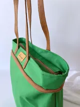 Bolso de lona color negro con detalles en cuero marrón, con bolsillo interno y forro de tela.