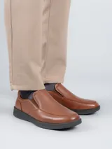 Zapato slip-on de cuero color marrón con suela negra y elástico lateral.