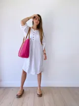 Vestido blanco de lino, corte holgado, con cuello redondo, mangas 3/4 con abertura y botones en el frente.