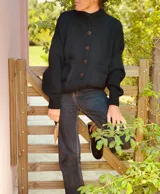 Cardigan negro de lana con cuello alto, cierre frontal con botones grandes, mangas largas y bolsillos delanteros.