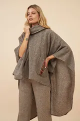 Poncho de lana color marrón con cuello alto, mangas 3/4 y bolsillo lateral con detalle de botones de cuero.