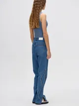 Pantalón de jean azul de tiro alto y corte oxford con apliques metálicos en bolsillos y laterales.