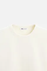 Sudadera negra de corte holgado, cuello redondo y mangas largas con puños acanalados.
