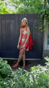 Vestido corto con estampado floral en tonos rosados y blancos sobre fondo marrón. Diseño con breteles finos y corte recto.