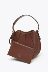 Bolso marrón formato saca con asa de mano y tira bandolera extraíble. Incluye cartera con bolsillo extraíble y cierre mediante botón imantado.