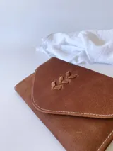 Billetera de cuero marrón con sistema de cierre con broche, monedero externo y detalle de hojas grabadas en la solapa.