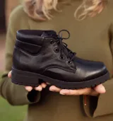 Bota acordonada color marrón claro de cuero, con suela de goma color beige y cordones finos blancos.