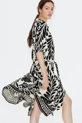 Vestido midi camisero con estampado floral en blanco y negro, cuello camisero, botonadura frontal y mangas cortas. Incluye cinturón extraíble para atar.