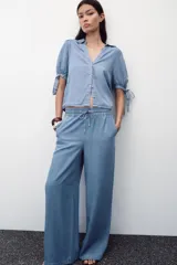 Pantalón celeste de tiro alto con cintura elástica ajustable con cordones, bolsillos delanteros y traseros, y pernera ancha.