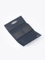 Billetera de cuero vacuno color azul celeste con efecto gastado. Cuenta con un cierre metálico tipo lipstick en forma de labios y múltiples compartimentos para tarjetas en su interior.