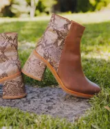 Bota corta de cuero marrón con detalle de cuero con textura de cocodrilo en el lateral y en el taco. Tiene cierre del lado interno y taco de madera forrada en cuero de 7cm.