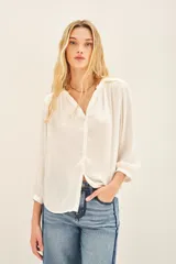 Camisa blanca de poliéster con cuello mao y mangas largas con frunces en hombros, mangas y espalda.