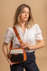 Bandolera pequeña de cuero sintético, con diseño color block en negro, blanco y naranja. Posee correa ajustable de tela con logo estampado y cierre principal.