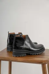 Botines negros de cuero con elástico lateral, detalle charol en el talón y suela track.