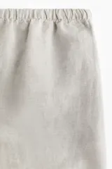 Short color crema de lino y viscosa, con cintura elástica ajustable con cordón, bolsillos laterales y aberturas laterales en el ruedo.