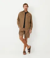 Camisa verde militar de manga larga en sarga de algodón, con cuello clásico, cierre frontal abotonado y dos bolsillos con solapa abotonada en el pecho.