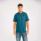 Remera tipo polo color petróleo con cuello de punto acanalado, puños de manga de punto plano y parche de silicona con el logo de Cat en el lado izquierdo del pecho.