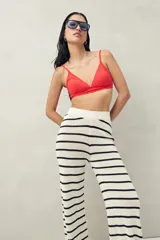 Pantalón largo de tejido de punto color crudo con rayas horizontales negras, corte ajustado y cintura alta.