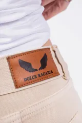 Pantalón Oxford color beige con corte ajustado en la parte superior y acampanado con aberturas en el ruedo.