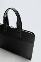 Maletín negro con acabado liso, compartimento principal con cierre de cremallera, bolsillo interior para dispositivos electrónicos de hasta 13 pulgadas, bolsillo interior con cierre de cremallera y dos asas de mano.
