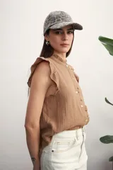 Camisa color amarillo pálido con cuello mao, sin mangas, con volados en los hombros y en el frente.