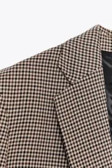 Blazer de cuello solapa y manga larga con estampado de pata de gallo en tonos marrones y negros. Bolsillos de vivo en delantero, detalle de coderas a contraste y cierre frontal con botón.