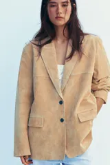 Blazer color camel confeccionada en piel de ante 100%. Diseño clásico con cuello solapa, escote pico, manga larga, bolsillos con solapa en delantero, forro interior combinado, bajo con abertura en espalda y cierre frontal con botones.