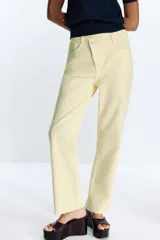 Jeans tobilleros de tiro alto color blanco, corte recto y cinco bolsillos. Cierre frontal cruzado con cremallera y botones.