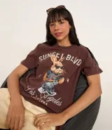 Remera marrón de algodón con cuello redondo y mangas cortas. Estampa frontal de un conejo con gafas de sol y texto "Sunset Blvd. Los Angeles California".