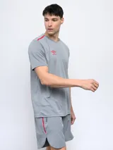 Remera deportiva gris de poliéster con detalles en rojo en hombros y logo de la marca en el pecho.