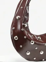 Bolso hobo de cuero sintético color bordó, con tachas plateadas.