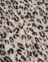 Pañuelo cuadrado de tela fina con estampado animal print en tonos beige, marrón y negro. Tiene borde con puntilla de crochet.