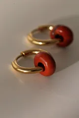 Par de aros dorados tipo argolla con dije de piedra natural color ladrillo.