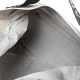 Bolso tote de cuero color taupe, con acceso superior con cierre y correa de hombro negra con letras blancas.