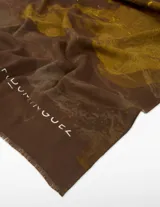 Chal rectangular con estampado abstracto en tonos marrón oscuro, rojo, amarillo mostaza y toques blancos/plateados. Presenta bordes deshilachados.