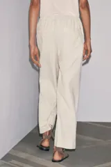 Pantalón culotte color crudo, de tiro medio, cintura elástica ajustable con cordones y bolsillos laterales ocultos en la costura.