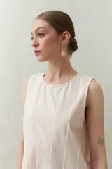 Vestido largo color beige, sin mangas, confeccionado en algodón con calados verticales y bordado tipo ojo de perdiz.