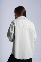 Sobrecamisa color beige de gabardina con cuello camisero, cierre frontal con botones a presión, dos bolsillos de parche en el pecho y corte holgado.